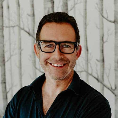 Person smiling with glasses and trees background